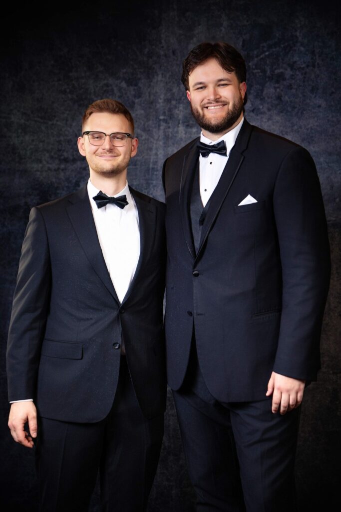 Two men posing in black suits